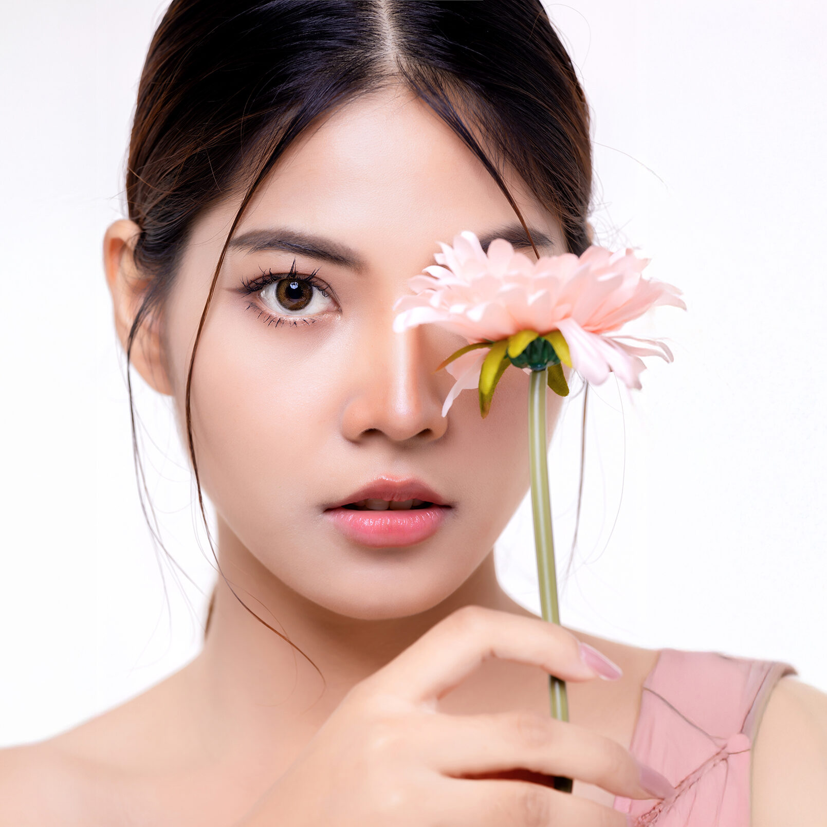 Beautiful make up Asian woman with perfect clear and fresh skin holding flower isolated over white background. Cosmetology, beauty and spa, wellness, Plastic surgery.